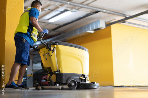 cleaning professional working in garage cleaning with sweeping machine