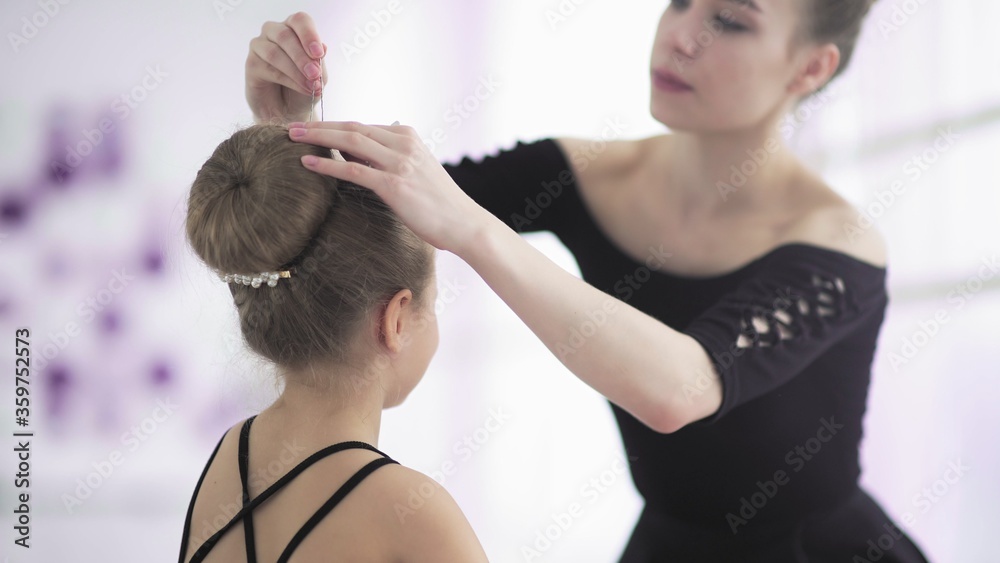 Young dance teacher fixing hairstyle to her student Young dance teacher fixing hairstyle to her student