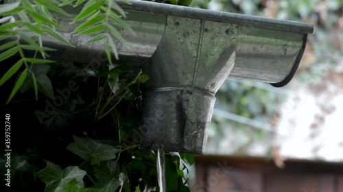 Rain water draining from roof pipeline, close-up photo