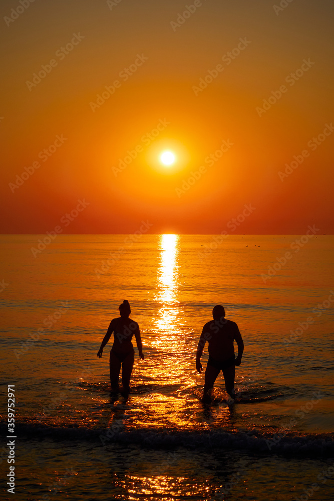 Silhouette of a couple swimming  in the sea at sunrise