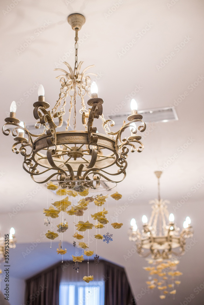 
The vintage chandelier is decorated with beige hanging threads with paper roses to create a romantic atmosphere.