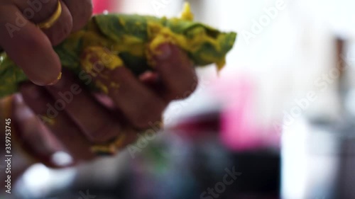 Indian woman tying a arvi arbi leaf marinated in flour and spices with a thin thread before deep frying it to make pakode and bhajiye a popular maharastran dish photo