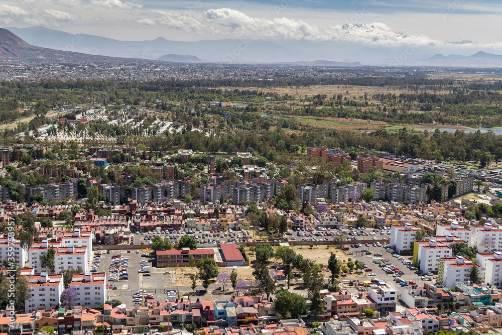 Aerial view of Mexico City with middle-class living zone, park and nature, and in the back snowed volcano