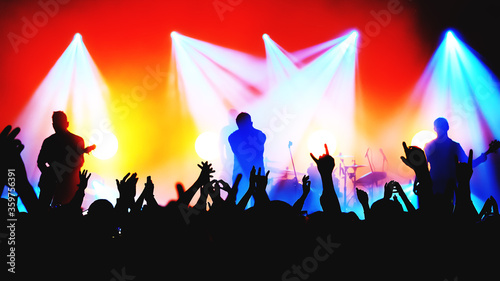 blurred silhouettes of rock band musicians on stage and crowd at a concert. atmosphere of a music festival. light spotlights