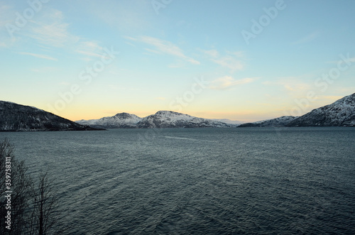 Mighty fjord surrounded by majestic snow covered mountain on clear cold day
