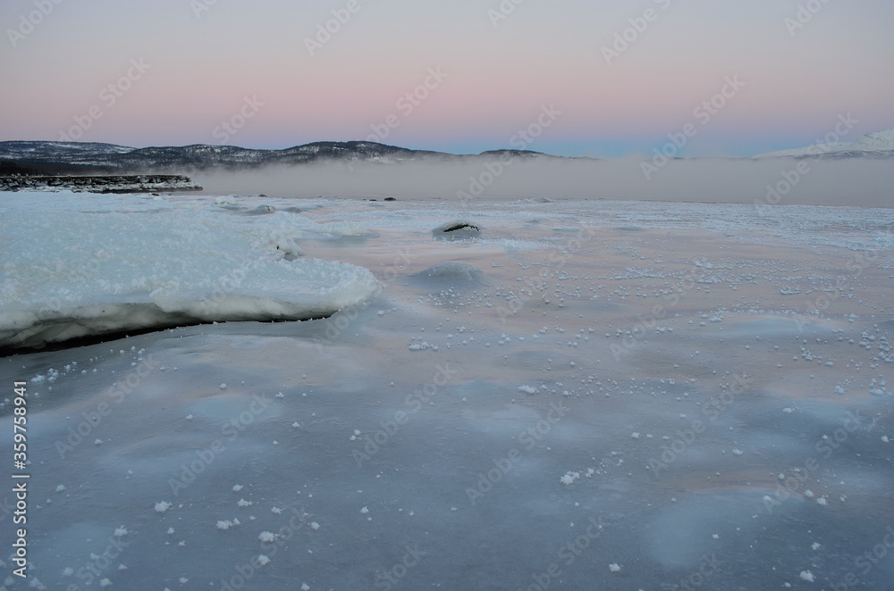 ice fog over frozen fjord with pink sunset sky