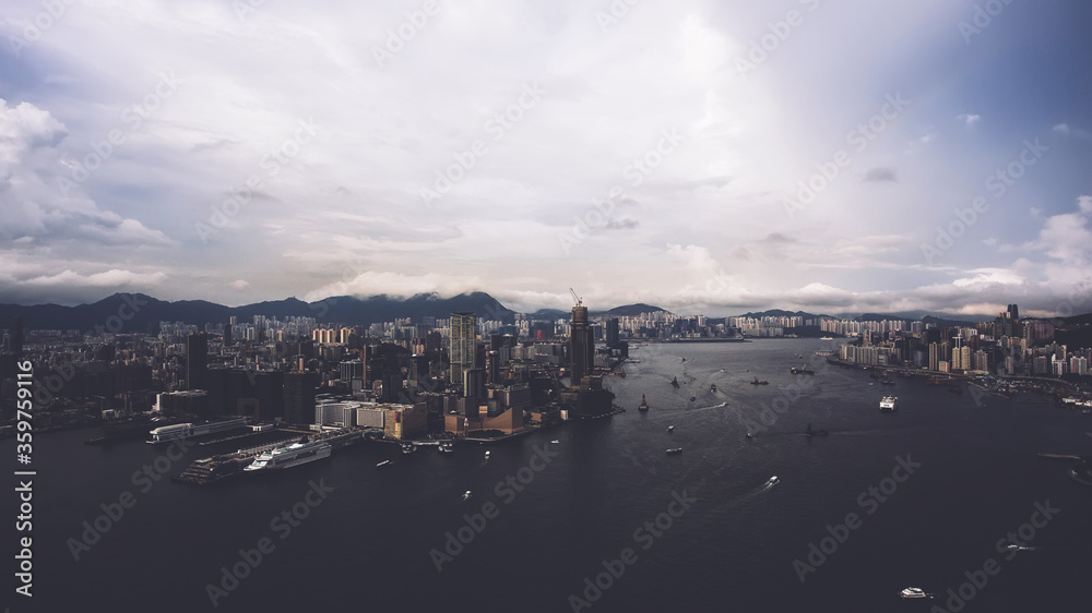 Aerial photo from flying drone of contemporary business district in China with financial centers and enterprises near sea bay with riding luxury yachts and boats. Beautiful dramatic sky over Hong Kong