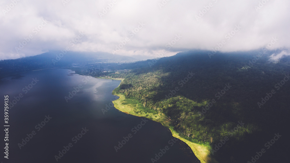 Aerial photo from flying drone of a wonderful nature landscape with island with tropical green plants near sea with calm beautiful waves. Amazing dramatic sky with thunderclouds over Indian Ocean