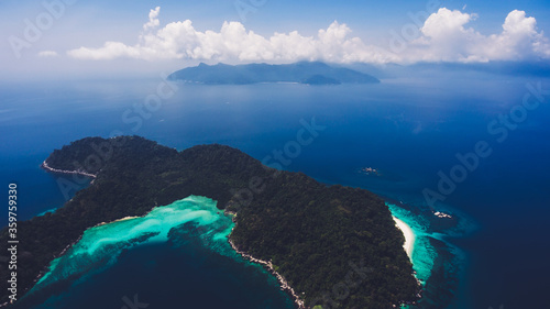 Aerial photo from flying drone of island with green tropical plants in open sea with blue water in sunny day in Bali. Amazing nature landscape in Indian Ocean with calm waves. Copy space for your text © BullRun