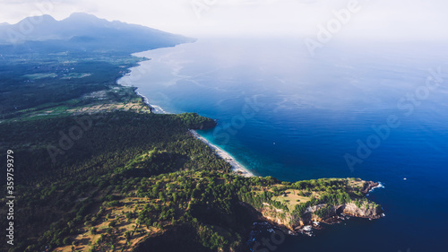 Aerial photo from flying drone of an amazing nature scenery with green island with tropical trees and blue sea with calm waves with copy space for your advertising text message. Beautiful Asian beach