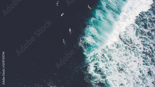 Top view from altitude of group the surfers are swimming on surfboards in ocean after big wave breaking at beautiful shoreline. Concept of aspiration and pursuit on example of fight with ocean current photo