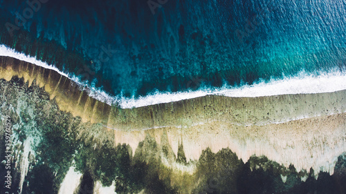 Top view aerial photo from flying drone of an amazingly beautiful sea with turquoise water and calm waves. Sandy beach with coral reef for snorkeling, perfect place for vacation holidays