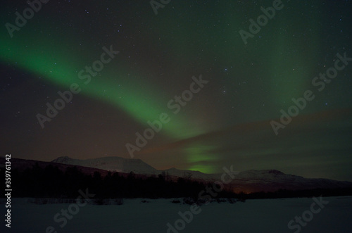 magnificent aurora borealis over frozen river bed and snowy mountain in the cold arctic circle night © Arcticphotoworks
