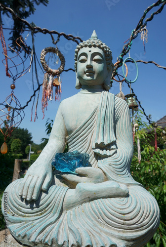 Sitzender meditierender Buddha mit einem blauen Glasstein in der Hand. Die Handbewegung bedeutet, die Erde zu rufen, um die Wahrheit zu bezeugen. photo
