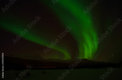 strong aurora borealis  northern light over frozen arctic circle landscape in winter night