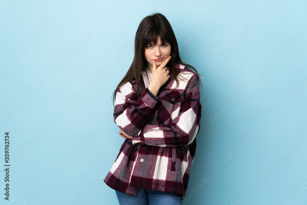 Fototapeta premium Teenager Ukrainian girl isolated on blue background thinking