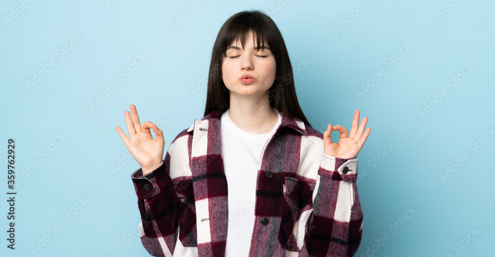 Teenager Ukrainian girl isolated on blue background in zen pose Teenager Ukrainian girl isolated on blue background in zen pose