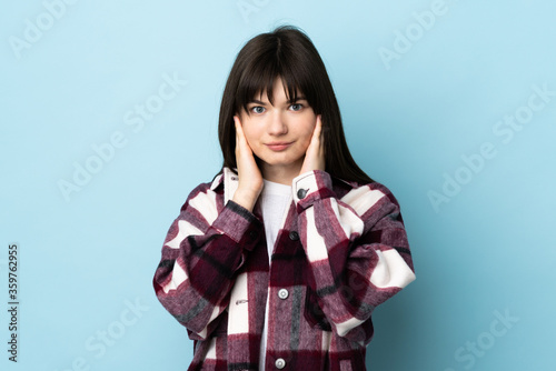 Teenager Ukrainian girl isolated on blue background frustrated and covering ears