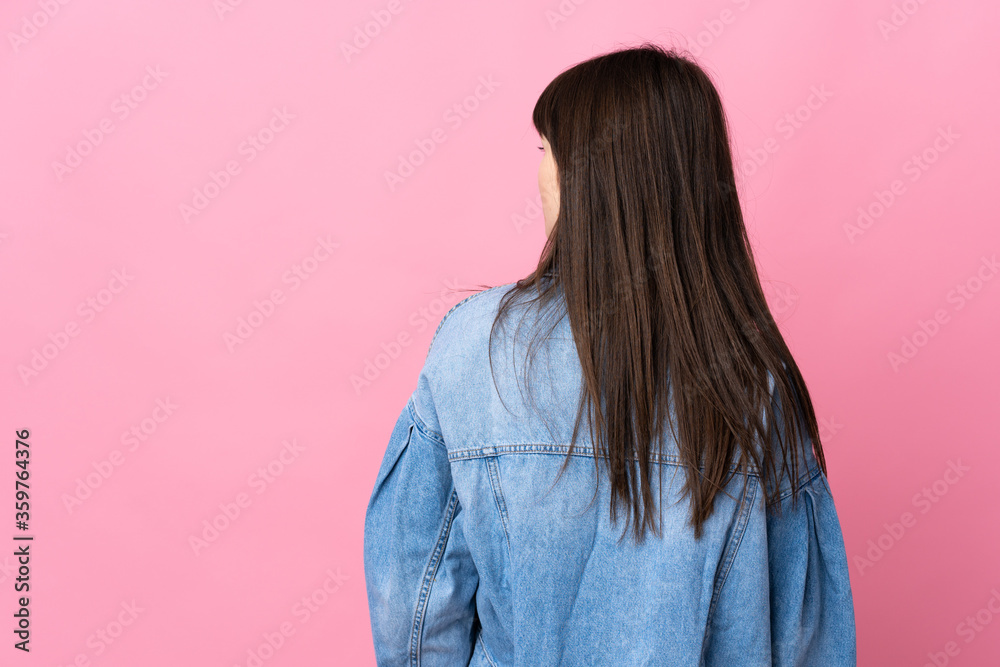 Fototapeta premium Young Ukrainian woman isolated on pink background in back position and looking side
