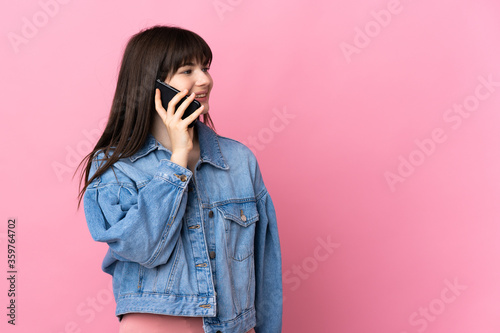 Young Ukrainian woman isolated on pink background keeping a conversation with the mobile phone with someone © luismolinero