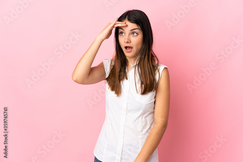 Young caucasian woman isolated on pink background doing surprise gesture while looking front