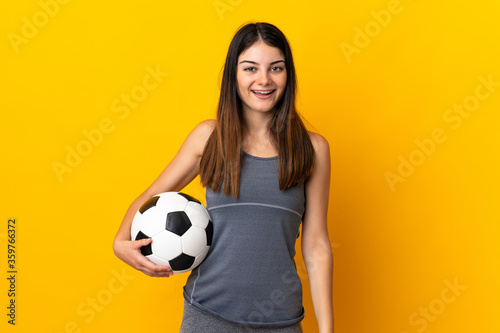 Young football player woman isolated on yellow background with surprise facial expression © luismolinero
