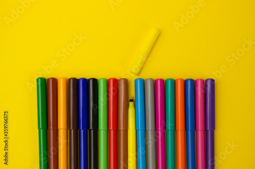 set of multi-colored felt-tip pens pencils on a yellow background