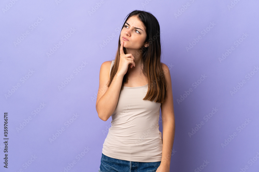 Young caucasian woman isolated on purple background having doubts while looking up