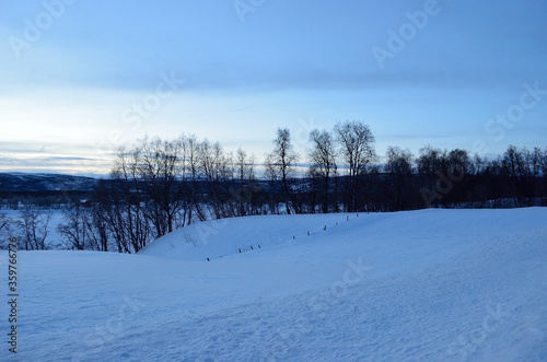 snowy field and mighty mountain landscape during the winter blue hour in northern Norway