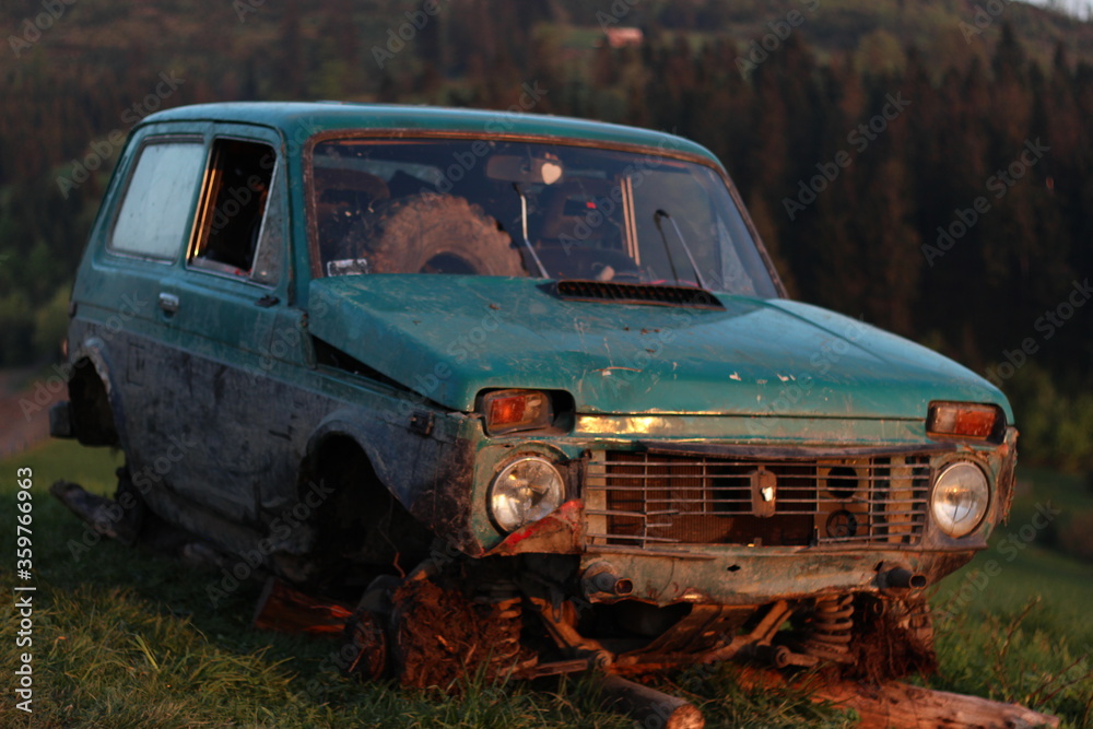 Vintage devastated car abandoned on a mountain peak by sunset