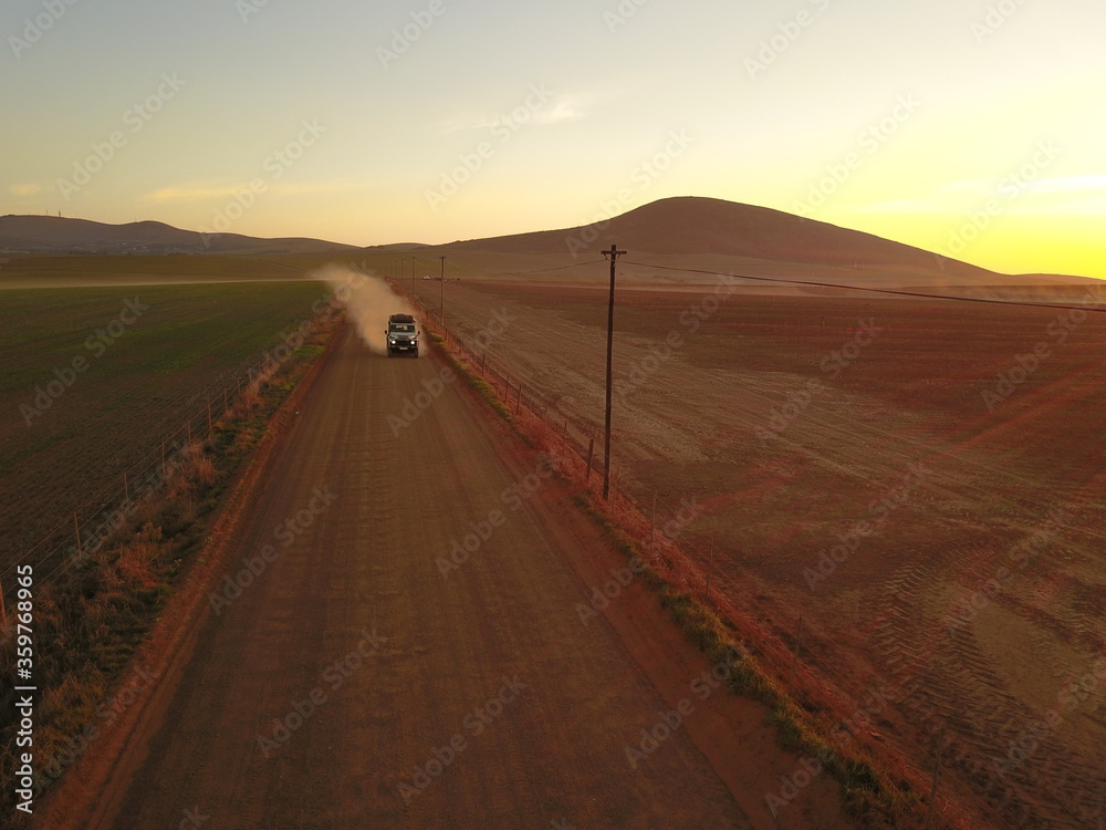 Off-roader vehicle on gravel road at sunset Off-roader vehicle on gravel road at sunset