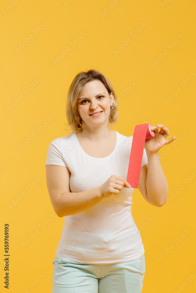 © dsheremeta - A therapist rolling kinesiology tape to demonstrate it on the yellow background. Alternative kinesio tape therapy, healthcare concept © dsheremeta - A therapist rolling kinesiology tape to demonstrate it on the yellow background. Alternative kinesio tape therapy, healthcare concept