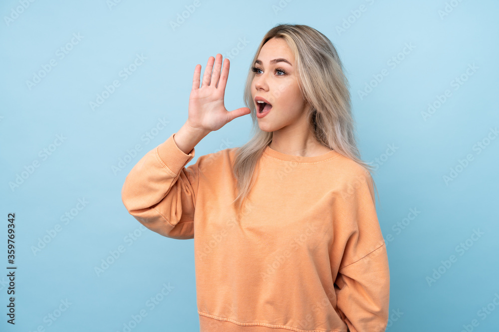 Teenager girl over isolated blue background shouting with mouth wide open Teenager girl over isolated blue background shouting with mouth wide open