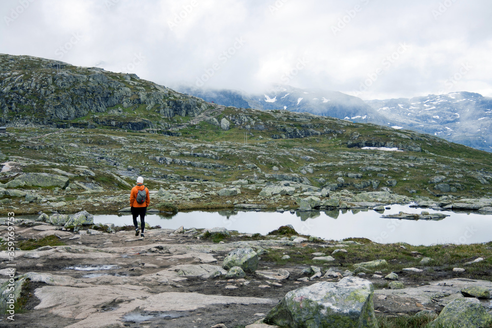 A man wearing orange jacket hiking in the mountains