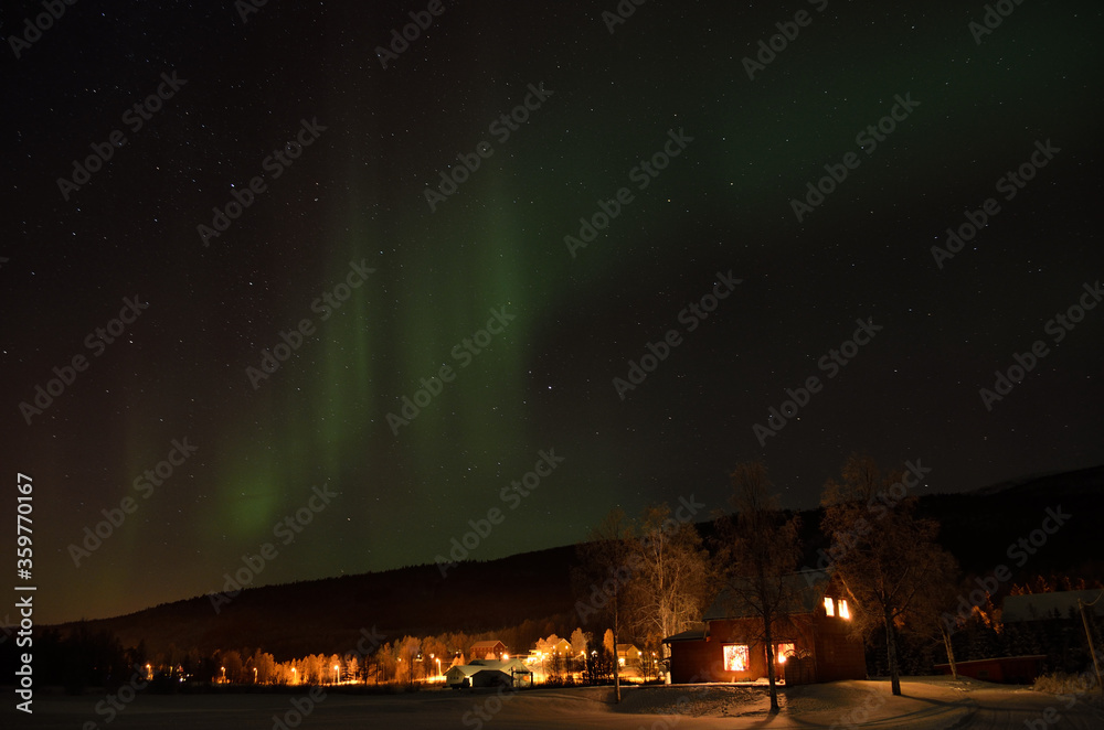 beautiful aurora borealis over houses at christmas time in the arctic circle