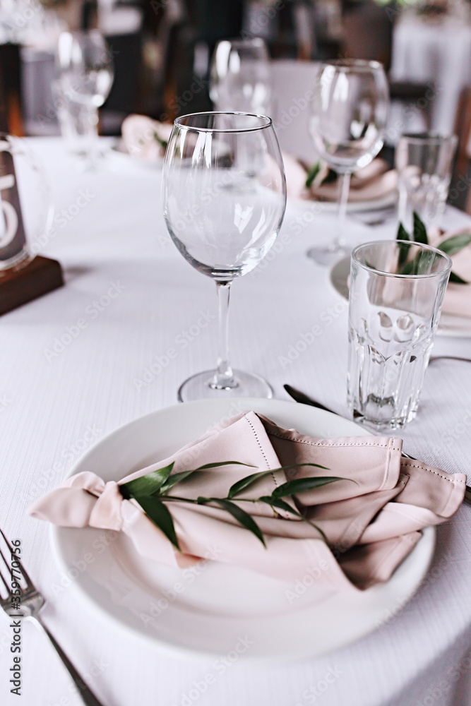 Wedding table setting. Tableware and decorations for serving a festive table. Plates, wine glasses and cutlery with decorative textile on white background. Table setting in restaurant. Wedding party. 