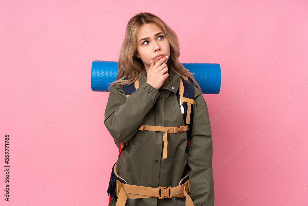 Teenager Russian mountaineer girl with a big backpack isolated on pink background having doubts and with confuse face expression Teenager Russian mountaineer girl with a big backpack isolated on pink background having doubts and with confuse face expression