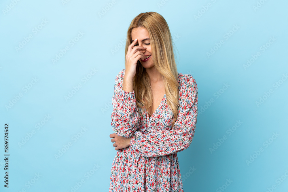 Young Uruguayan blonde woman over isolated blue background laughing Young Uruguayan blonde woman over isolated blue background laughing