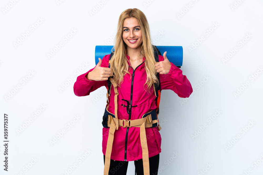 Young mountaineer woman with a big backpack over isolated white background giving a thumbs up gesture Young mountaineer woman with a big backpack over isolated white background giving a thumbs up gesture
