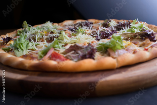 closeup pizza on a tray, with vegetables and meat, in a rustic style. Unusual angle. Salad, vegetable pizza, meat lunch. Friendly pizza. The texture of the pizza. Food. Bad food. Carbohydrate food