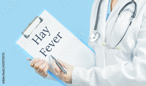 Doctor with HAY FEVER text against blue background. Seasonal allergy symptoms, triggers complications concept.