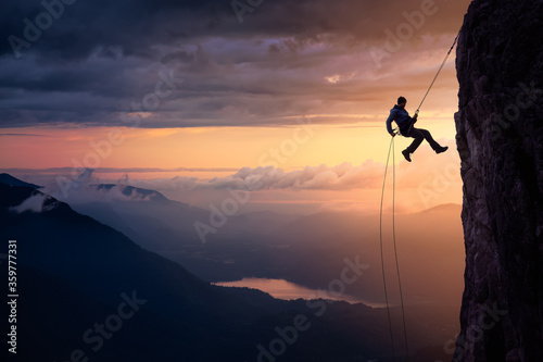 Epic Adventurous Extreme Sport Composite of Rock Climbing Man Rappelling from a Cliff. Mountain Landscape Background from British Columbia, Canada. Concept: Explore, Hike, Adventure, Lifestyle photo