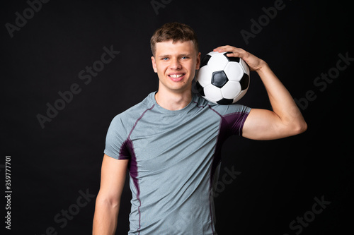Handsome young football player man over isolated black wall