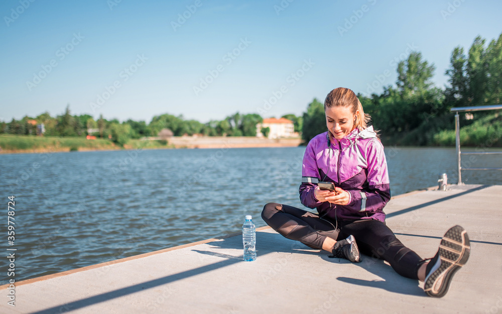 Active girl browsing music on her phone during workout outdoors
