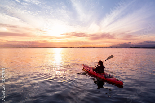 Sea Kayaking in calm waters during a colorful and vibrant sunset. Adventure Girl in Red Kayak. Location: White Rock, Vancouver, British Columbia, Canada. © edb3_16