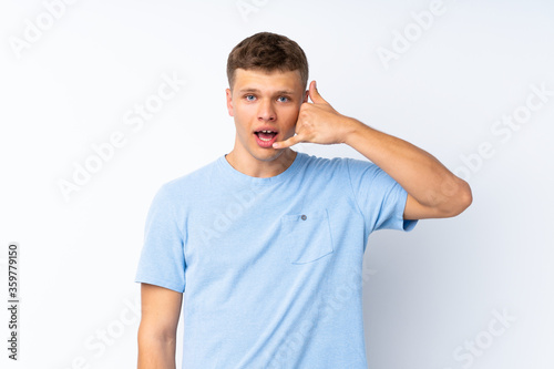 Young handsome man over isolated white background making phone gesture. Call me back sign