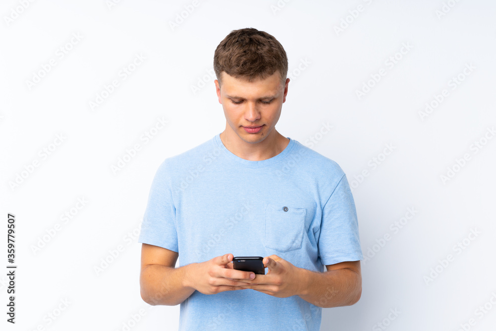 Young handsome man over isolated white background sending a message with the mobile Young handsome man over isolated white background sending a message with the mobile