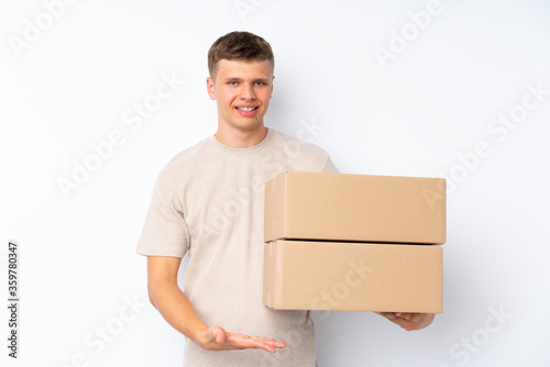 Young handsome man over isolated white background holding a box to move it to another site