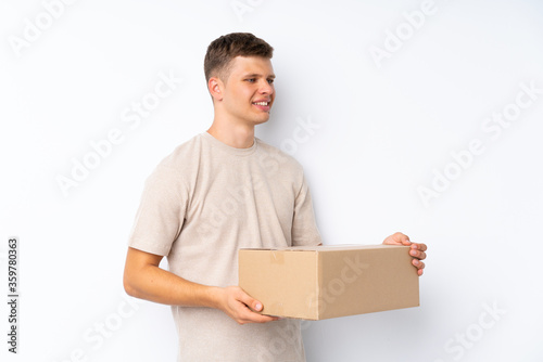 Young handsome man over isolated white background holding a box to move it to another site