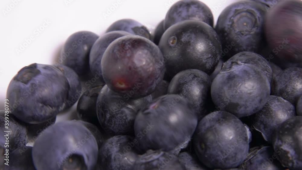 Close-up of large blueberries falling into the white bowl in slow motion